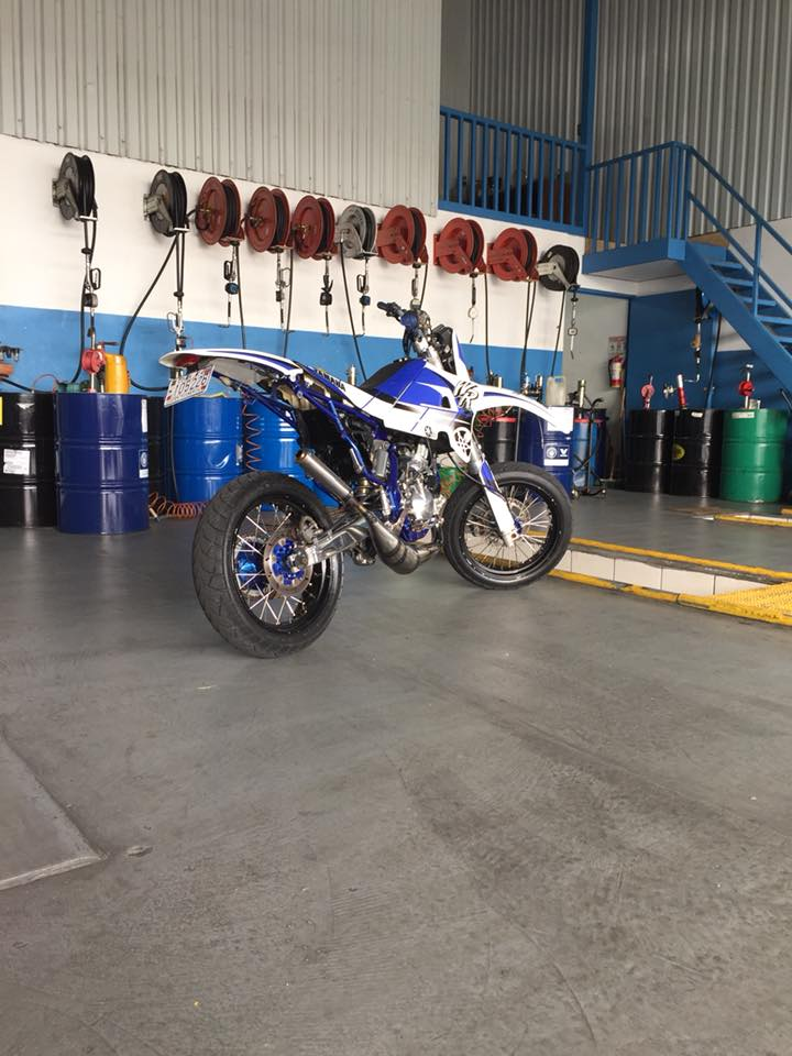 Moto Yamaha en el taller con barriles de aceite y carretes de lubricación